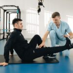 A physiotherapist assists a male patient during a rehabilitation session in a modern clinic. - Photo by Funkcinės Terapijos Centras on Pexels