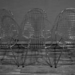 Three metal wire chairs aligned indoors against a textured wall. - Photo by Hajo Merz on Pexels