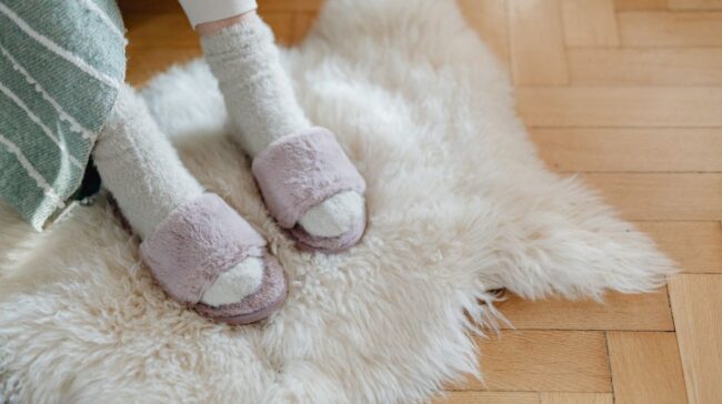 Warm and cozy feet in plush slippers resting on a soft fur rug for relaxation. - Photo by https://kaboompics.com/ on Pexels